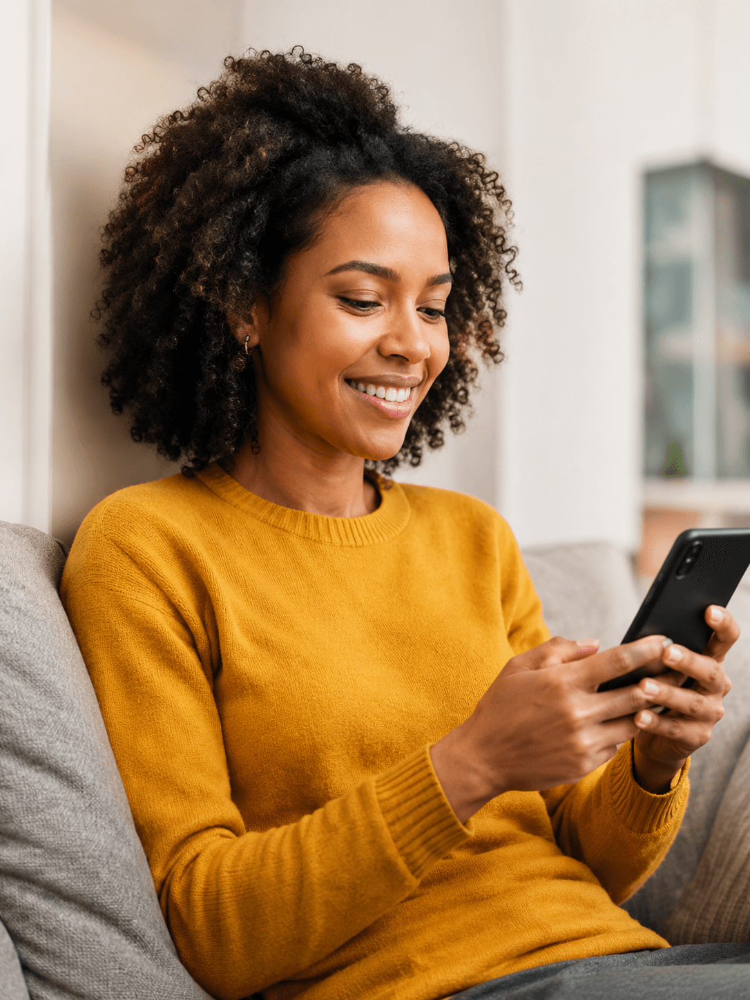 Woman smiling while using her phone at home